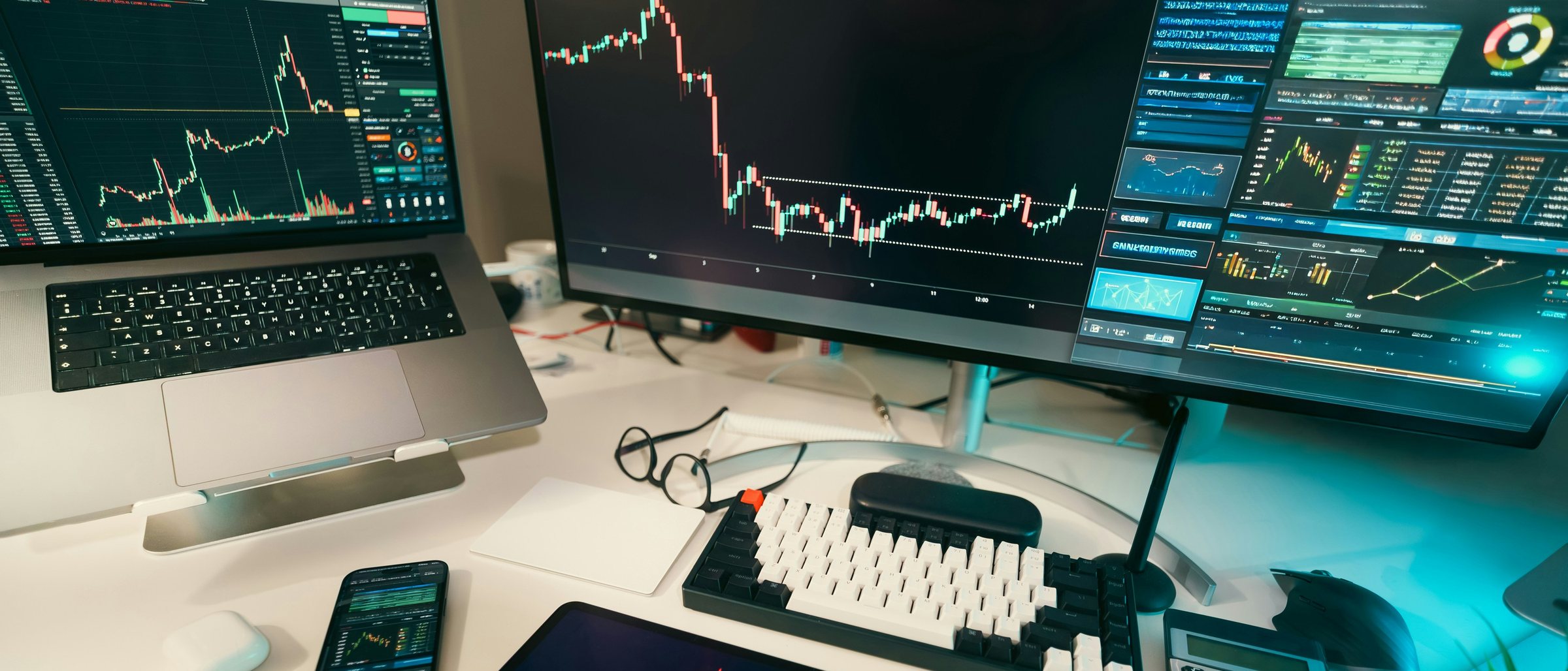 A trading desk at night: candlestick charts and market data across several screens